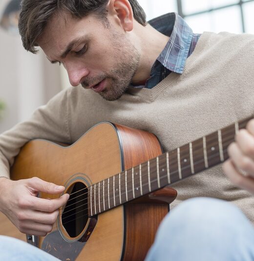 homme-regardant-la-guitare-et-joue compositeur arrangeur rhone-alpes-chanson personnalisee auvergne rhone alpes-sound design-mixage france-creation de musique-musique de mariage rhone-alpes-stage de guitare vienne
